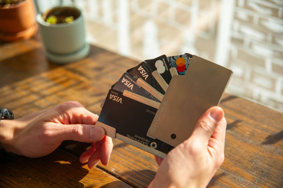 Hands using mobile banking app to enhance account security on metal credit card